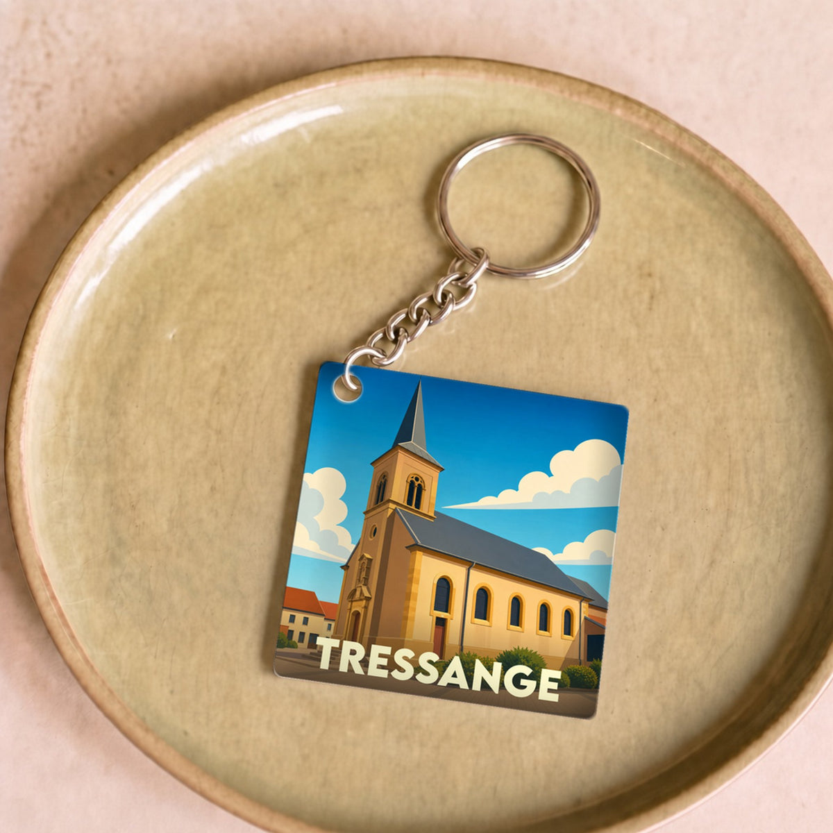 Porte-clés souvenir de la ville de Tressange avec une illustration stylisée de son église.