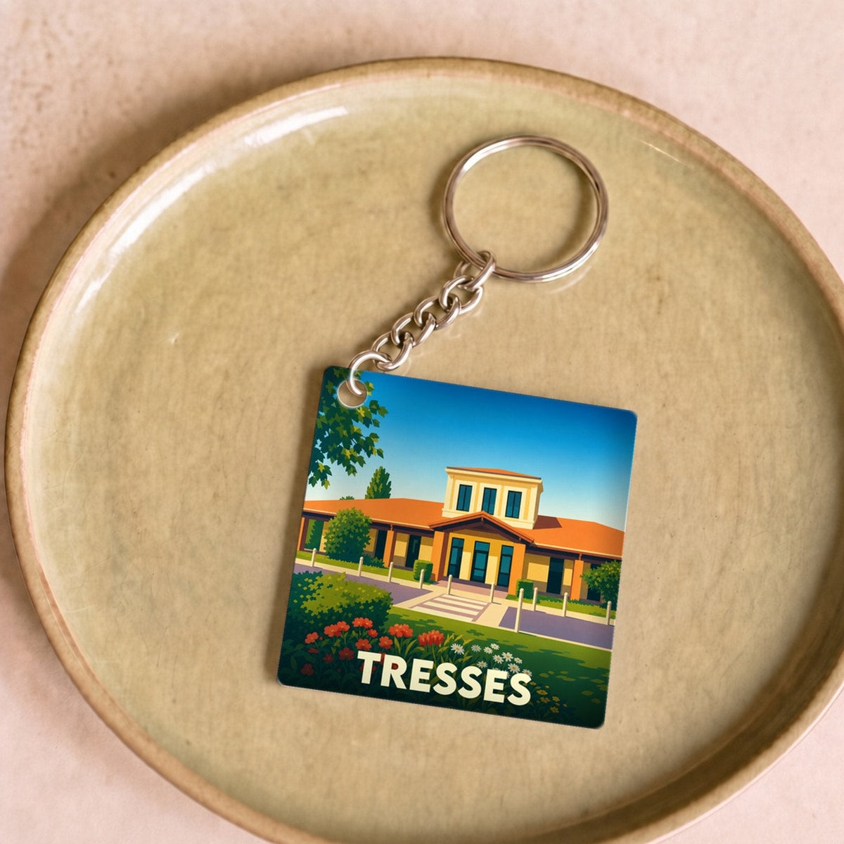 Porte-clés souvenir de la ville de Tresses avec une illustration stylisée d'un bâtiment sous un ciel bleu.