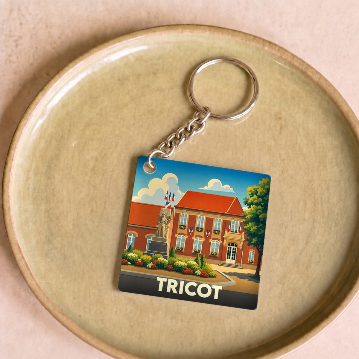Porte-clés souvenir de la ville de Tricot avec une illustration stylisée.