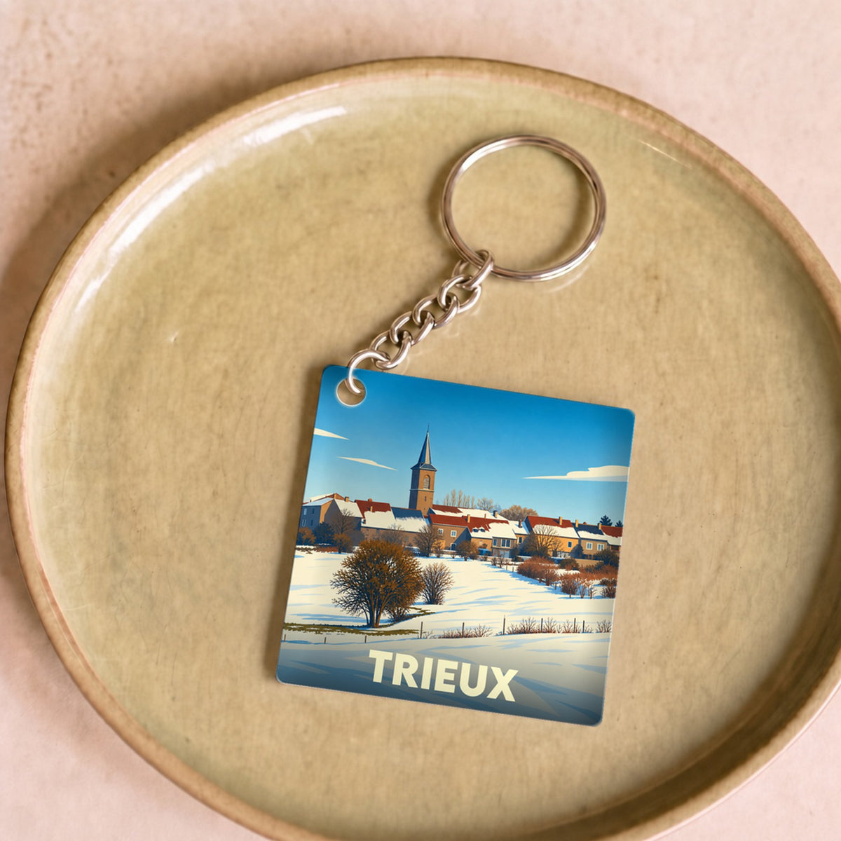 Porte-clés souvenir de la ville de Trieux avec une illustration hivernale stylisée.
