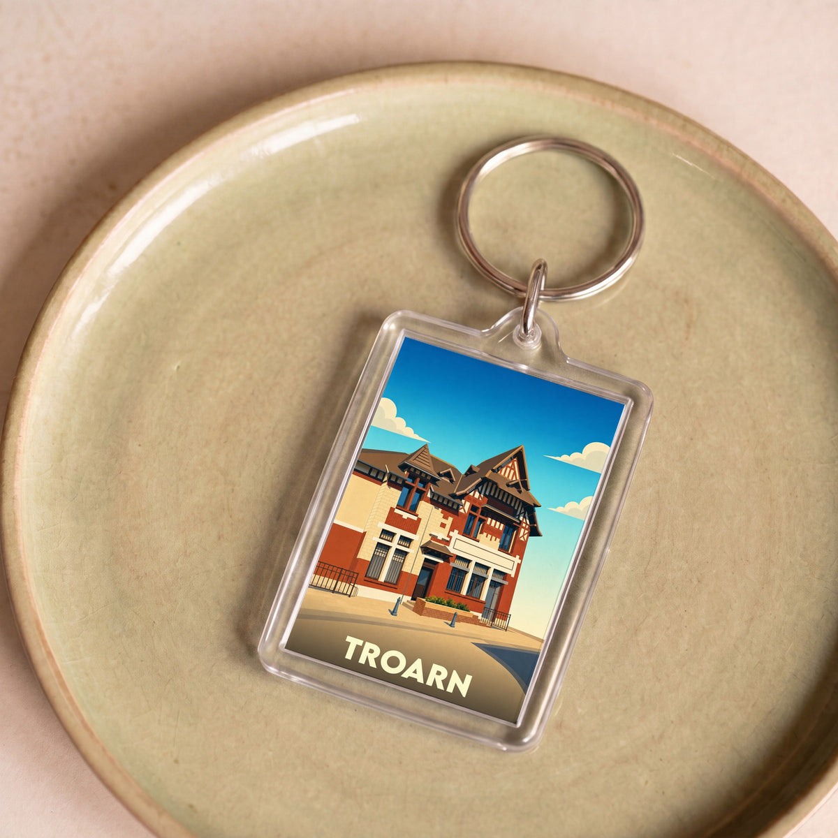 Porte-clés souvenir de la ville de Troarn avec une illustration stylisée d'un bâtiment remarquable.
