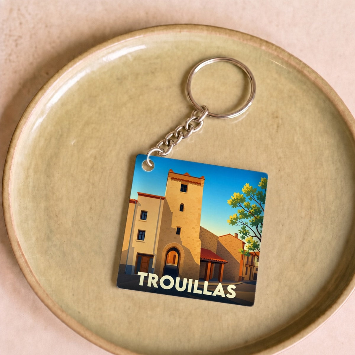 Porte-clés souvenir de la ville de Trouillas avec une illustration stylisée de son architecture.