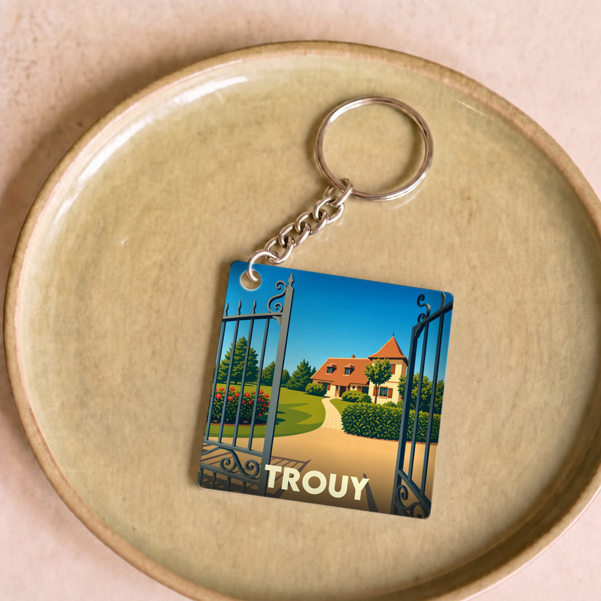 Porte-clés souvenir de la ville de Trouy avec une illustration stylisée d'une propriété.