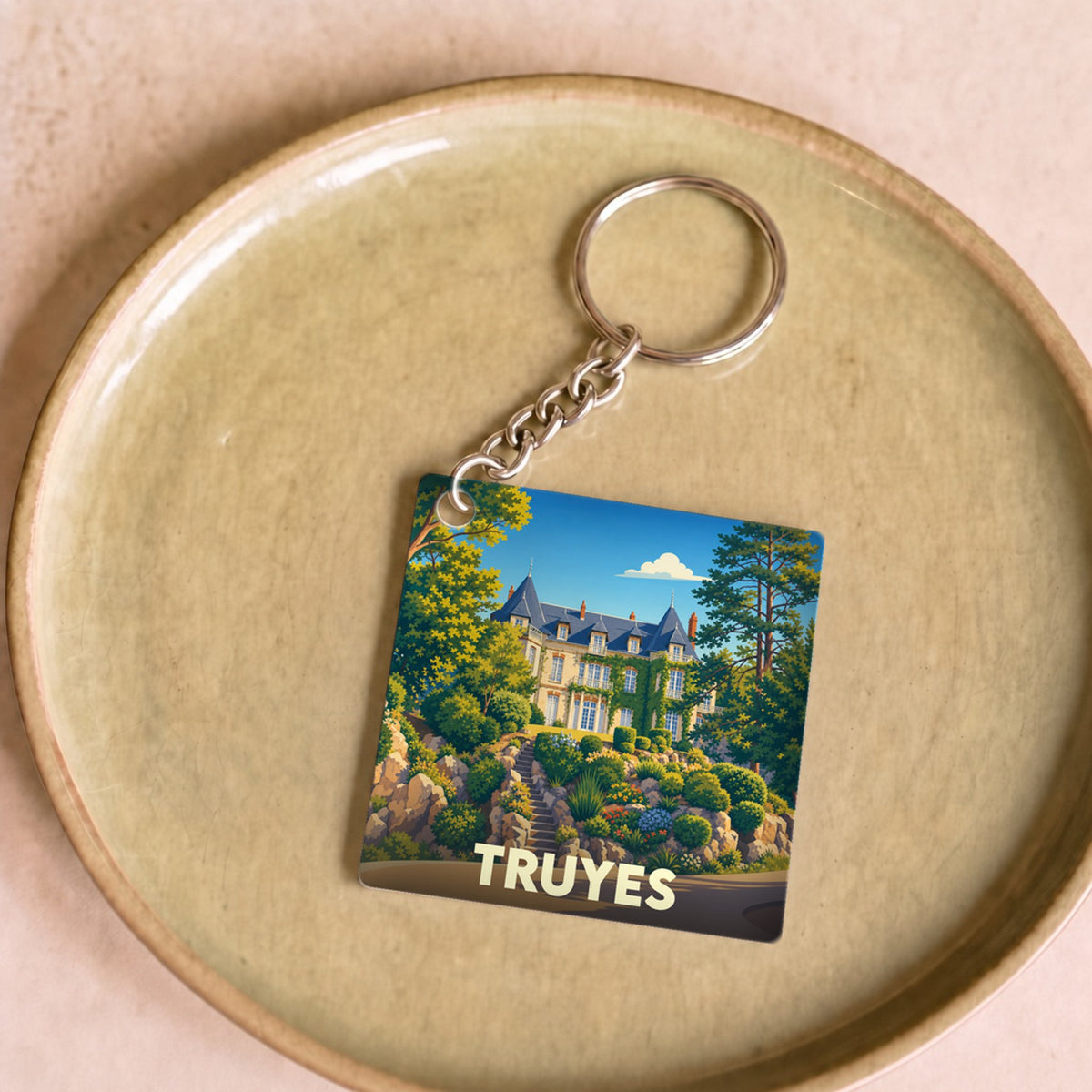 Porte-clés souvenir de la ville de Truyes avec une illustration stylisée d'un château entouré de verdure.