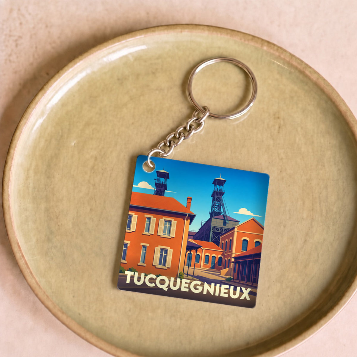 Porte-clés souvenir de la ville de Tucquegnieux avec une illustration stylisée montrant des chevalements de mine.