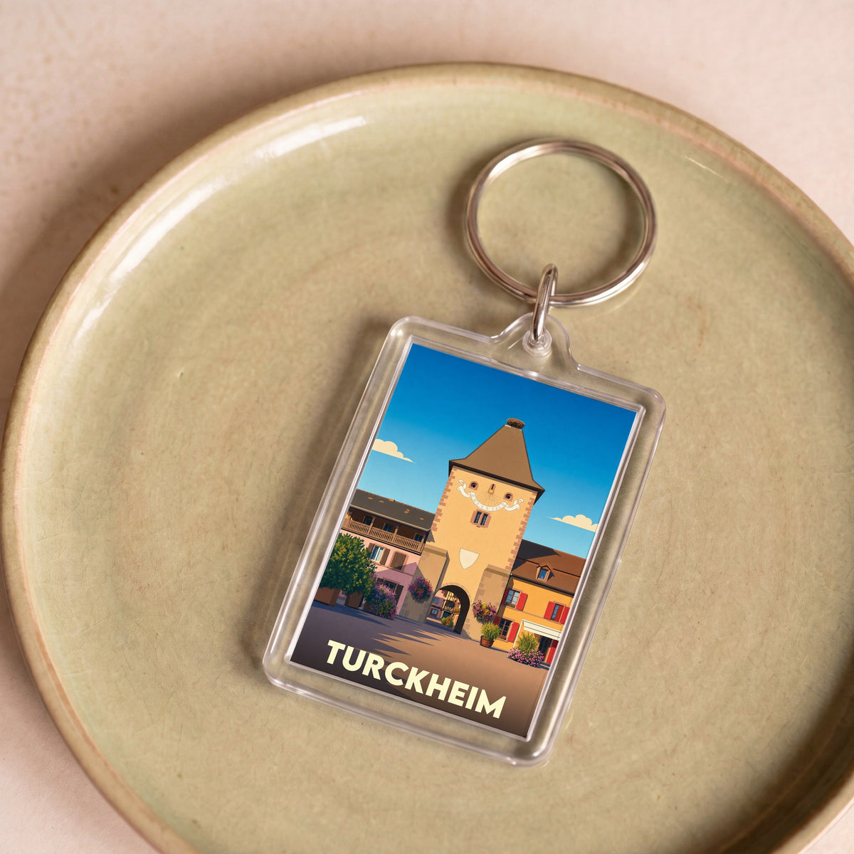 Porte-clés souvenir de la ville de Turckheim avec une illustration stylisée de sa tour historique.