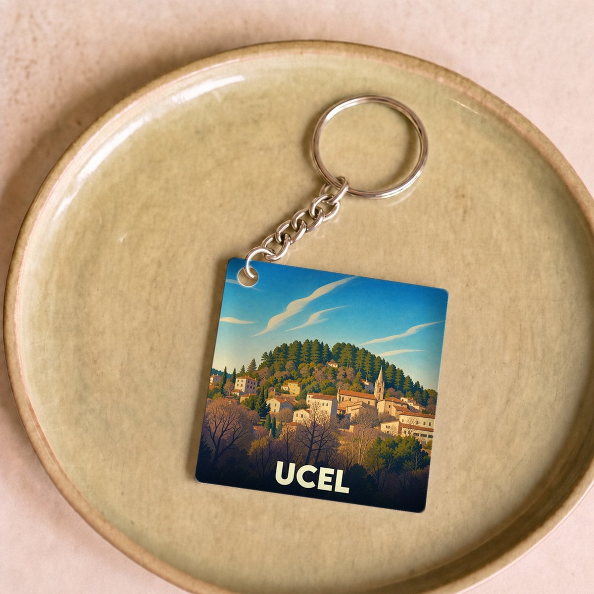 Porte-clés souvenir de la ville de Ucel avec une illustration stylisée.