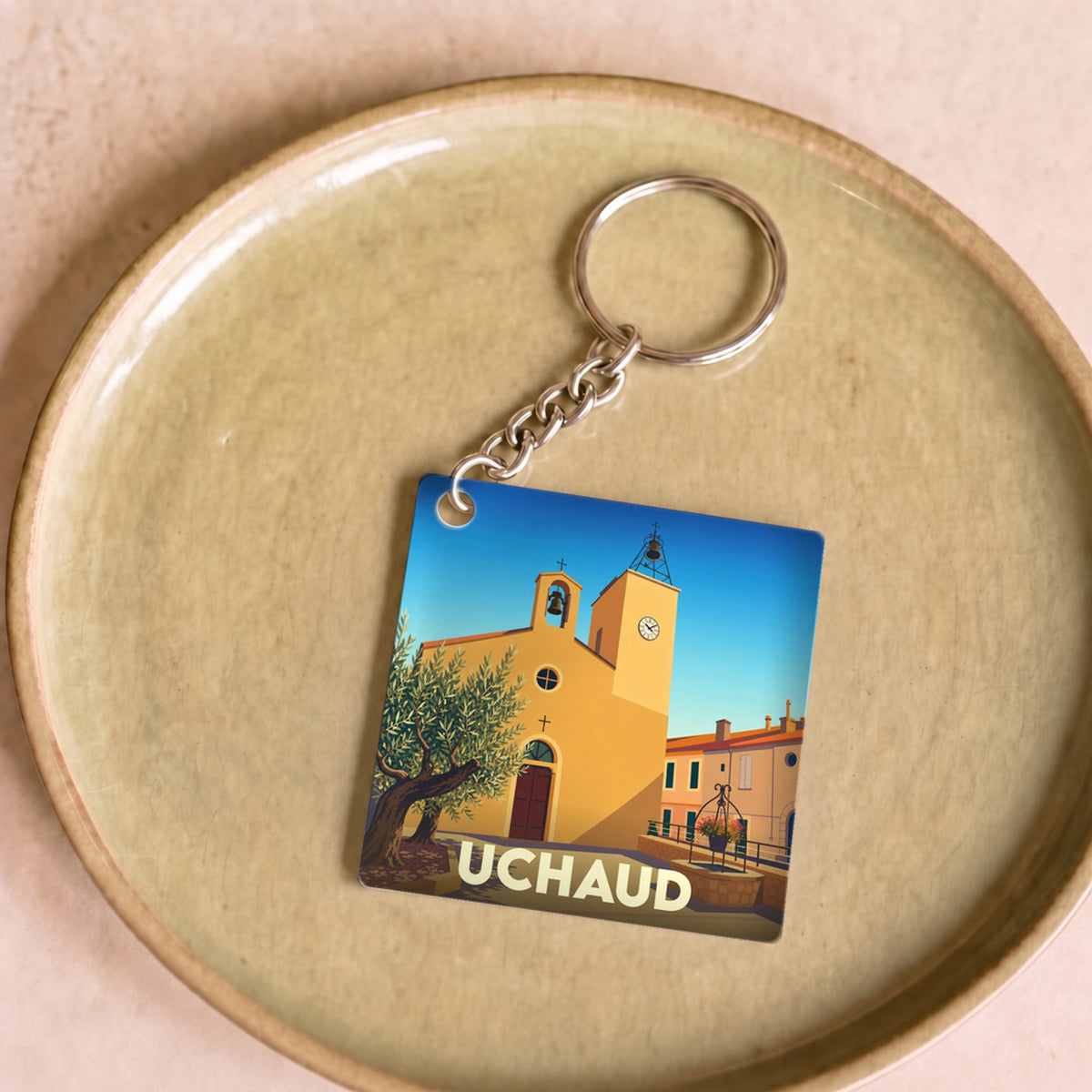 Porte-clés souvenir de la ville d'Uchaud avec une illustration stylisée.