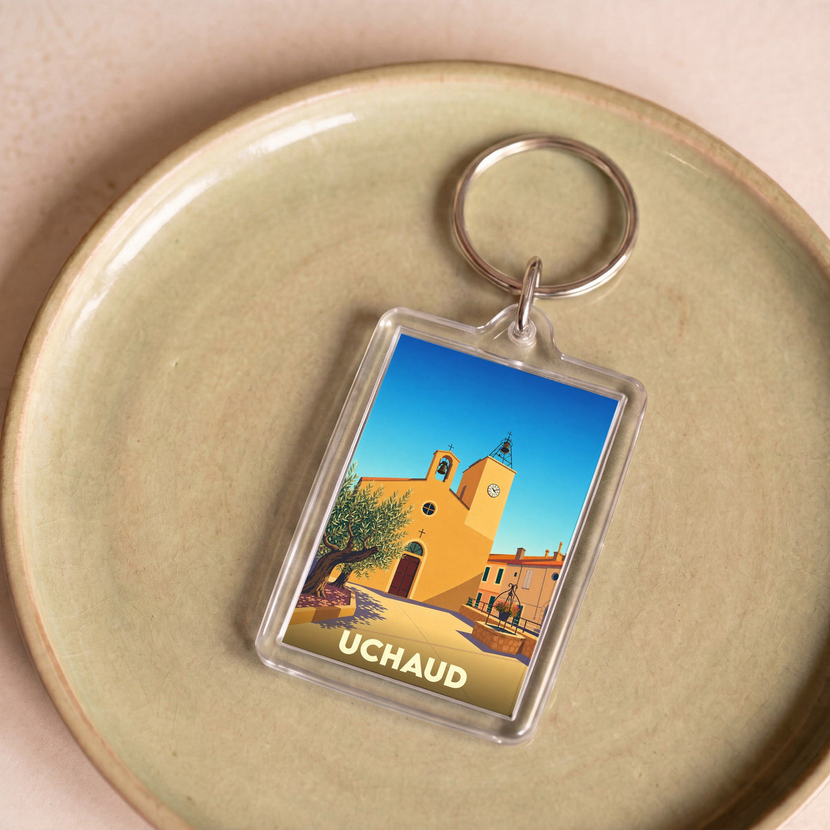 Porte-clés souvenir de la ville d'Uchaud avec une illustration stylisée.