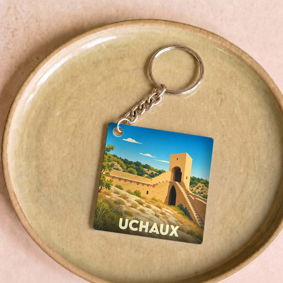 Porte-clés souvenir de la ville d'Uchaux avec une illustration stylisée de son patrimoine.