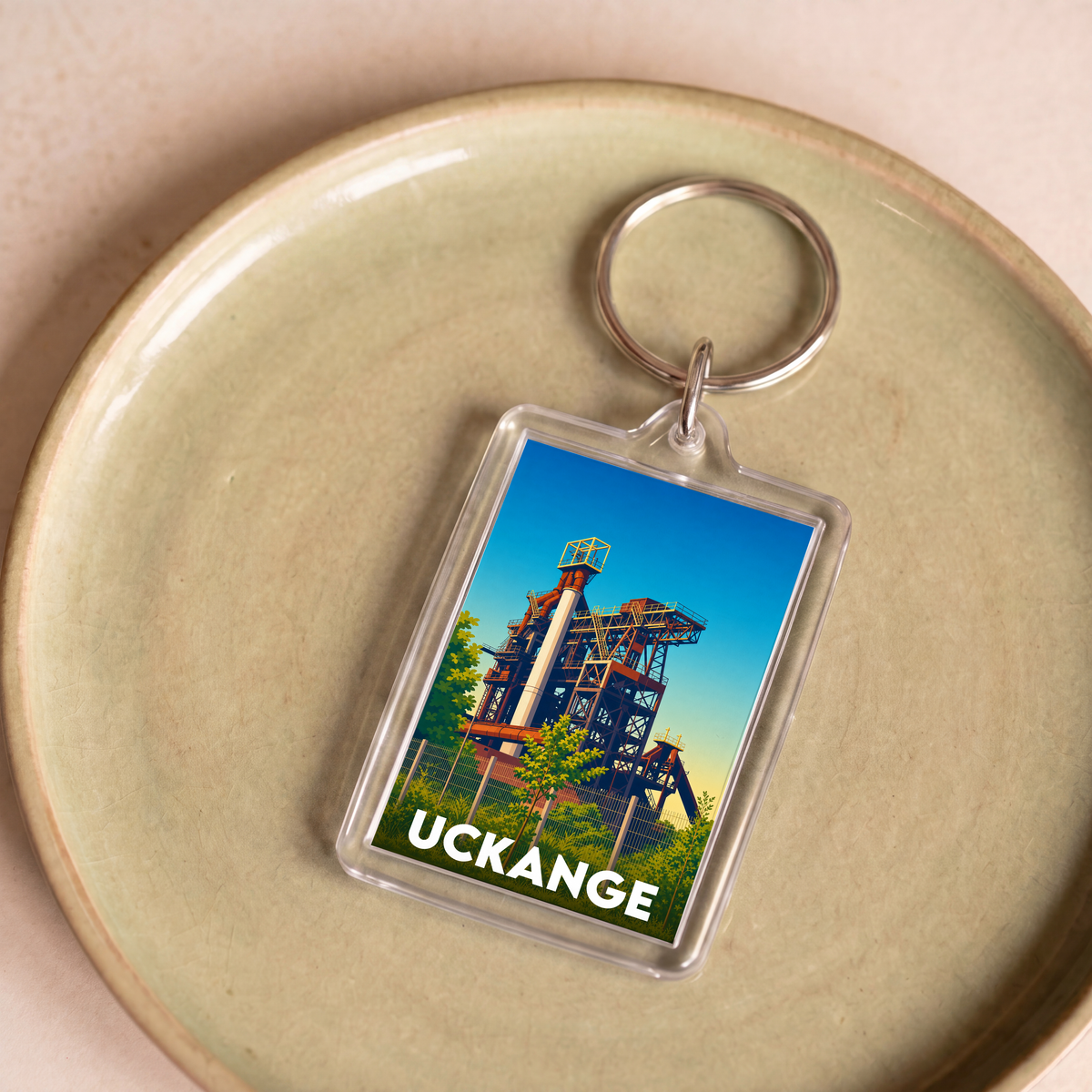 Porte-clés souvenir de la ville d'Uckange avec une illustration stylisée d'un haut-fourneau.