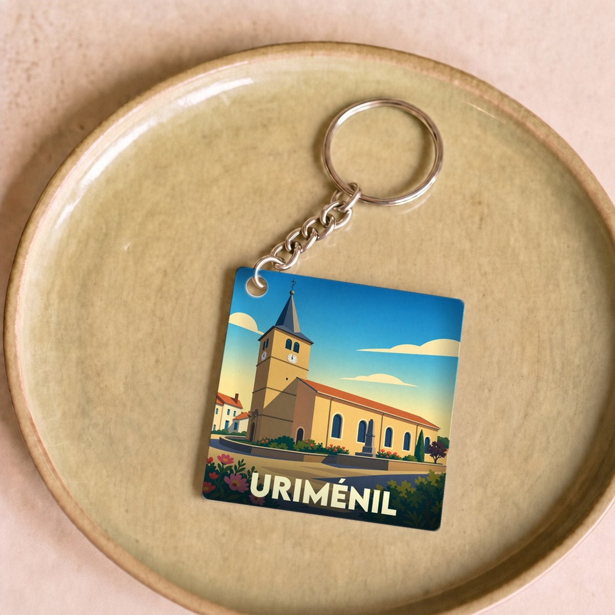 Porte-clés souvenir de la ville de Uriménil avec une illustration stylisée de son église.