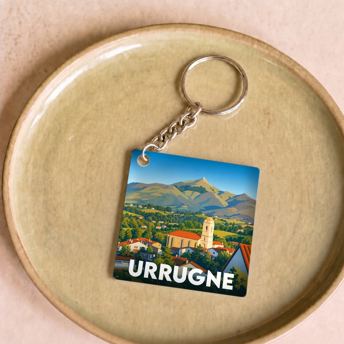 Porte-clés souvenir de la ville d'Urrugne avec une illustration stylisée de son paysage montagneux.