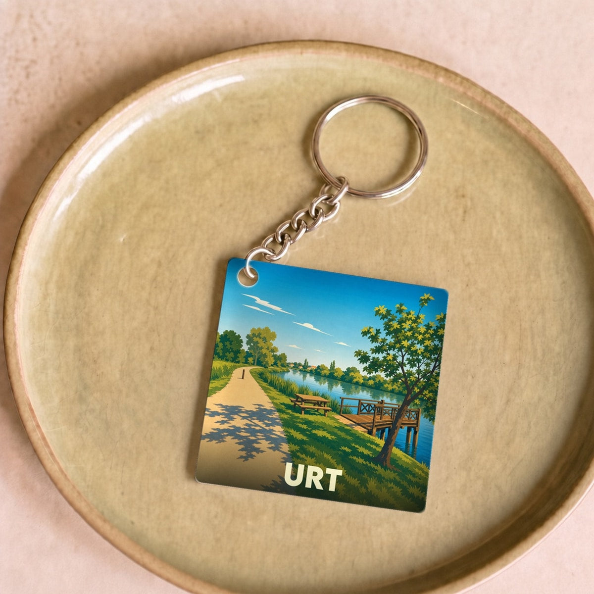 Porte-clés souvenir de la ville de Urt avec une illustration stylisée d'un paysage de bord de l'eau.
