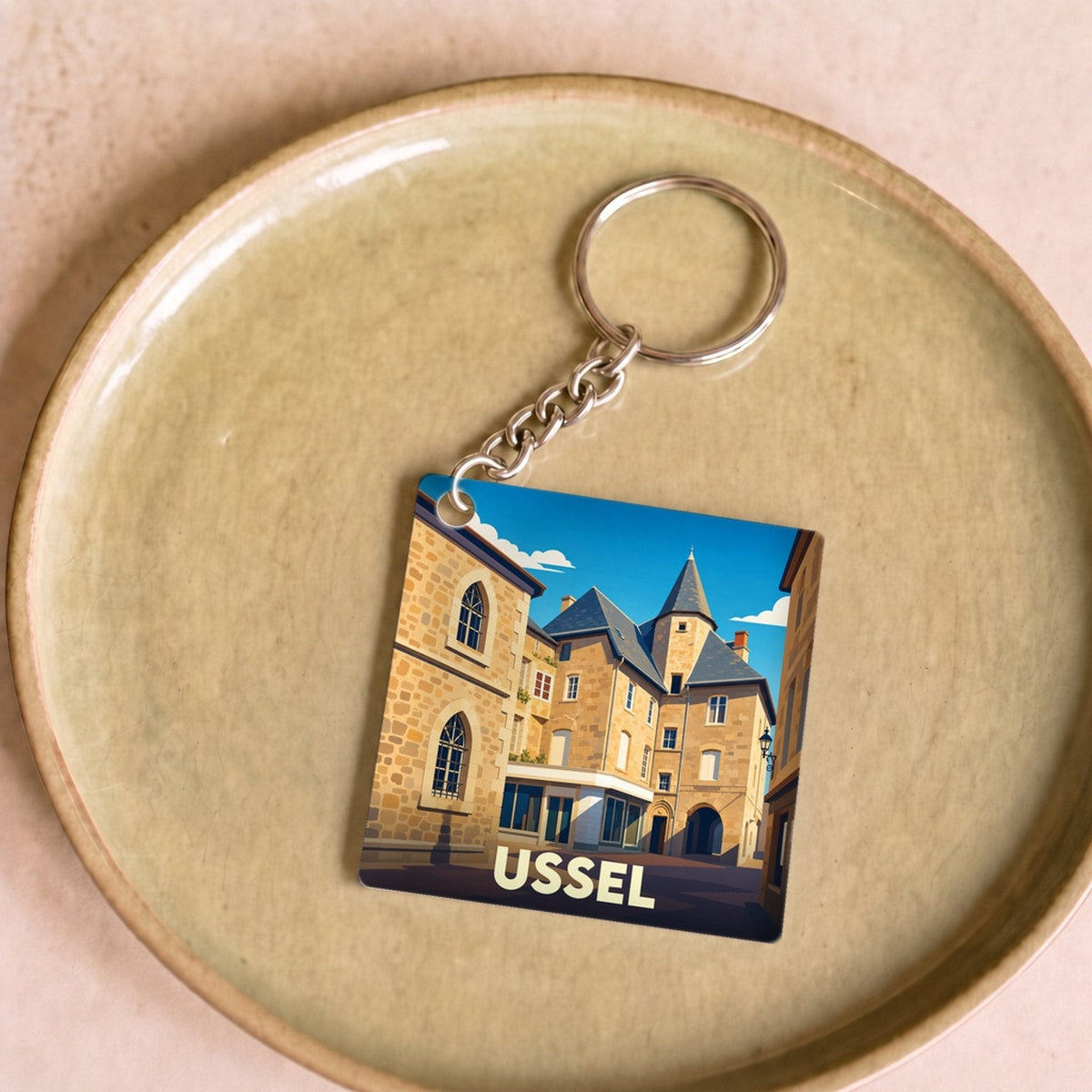 Porte-clés souvenir de la ville d'Ussel avec une illustration stylisée de son architecture historique.