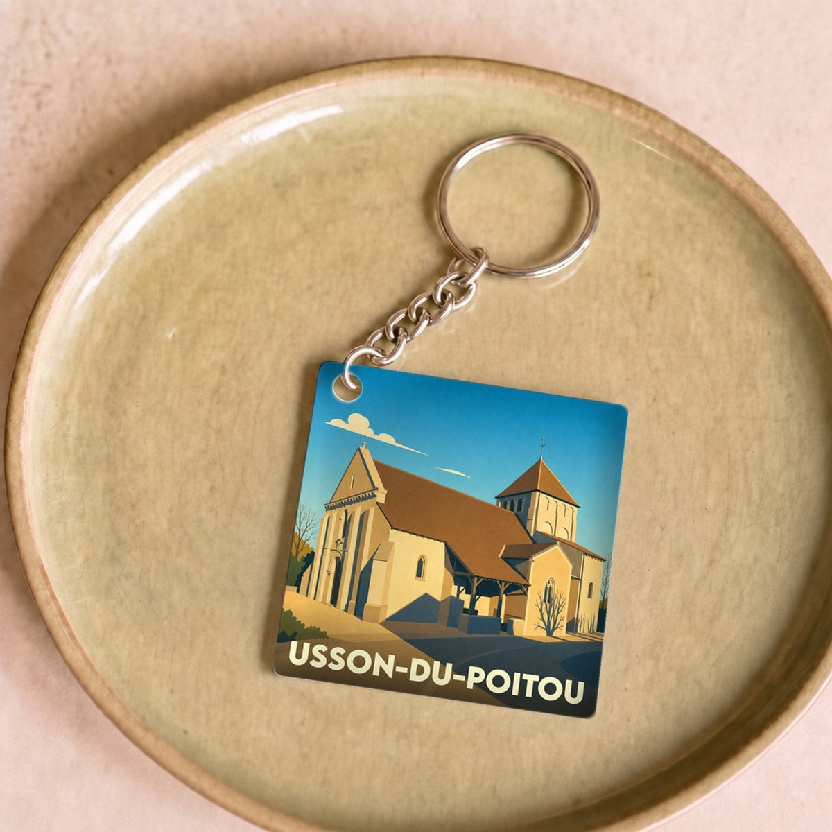 Porte-clés souvenir de la ville d'Usson-du-Poitou avec une illustration stylisée de son église.