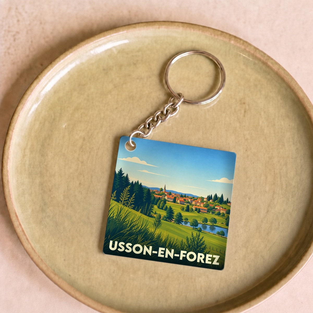 Porte-clés souvenir de la ville de Usson-en-Forez avec une illustration stylisée de son paysage.