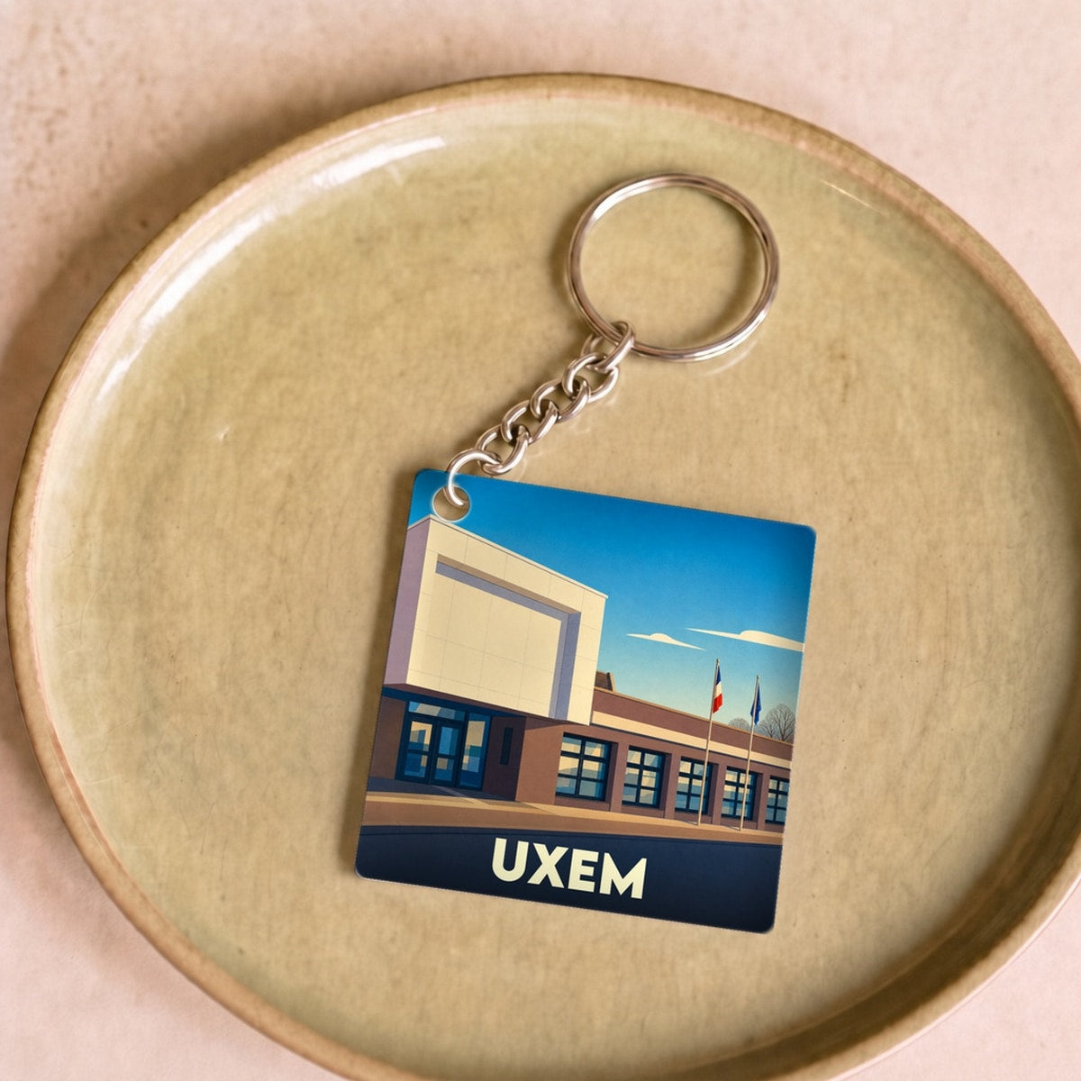 Porte-clés souvenir de la ville d'Uxem avec une illustration stylisée de sa mairie.