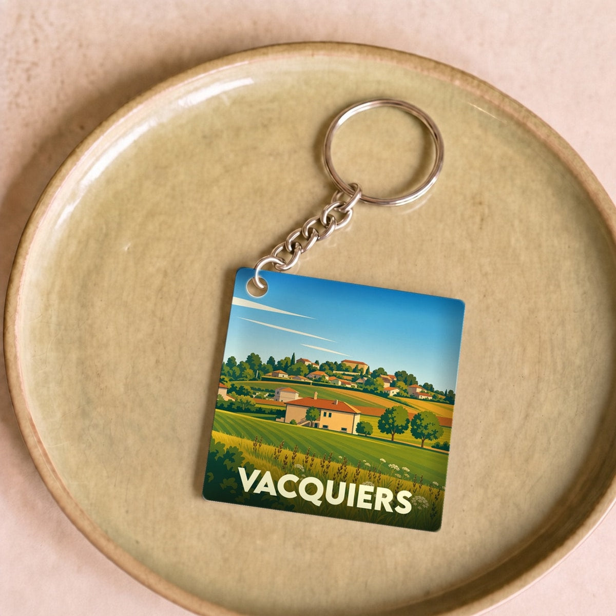 Porte-clés souvenir de la ville de Vacquiers avec une illustration stylisée de son paysage rural.