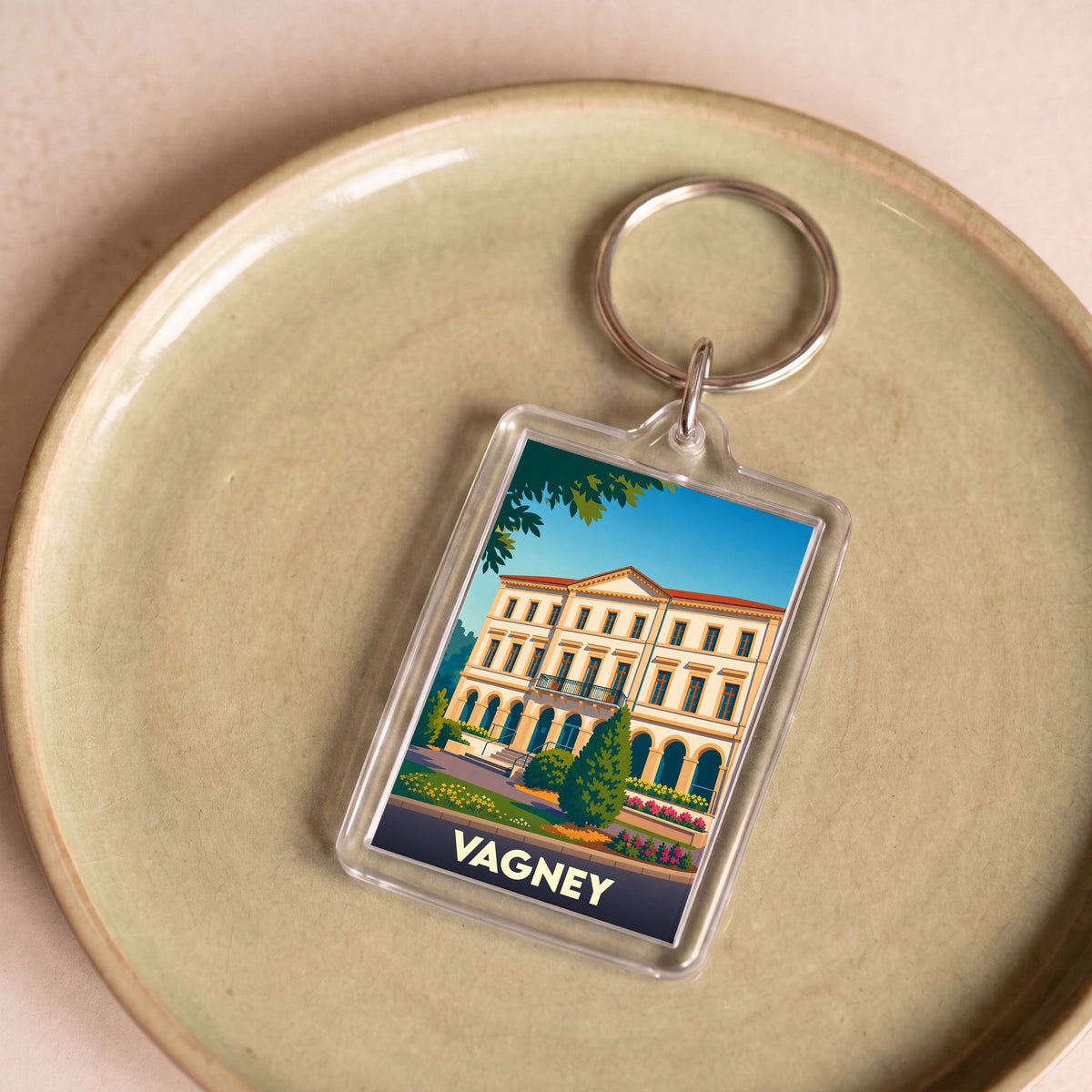 Porte-clés souvenir de la ville de Vagney avec une illustration stylisée d'un bâtiment historique.