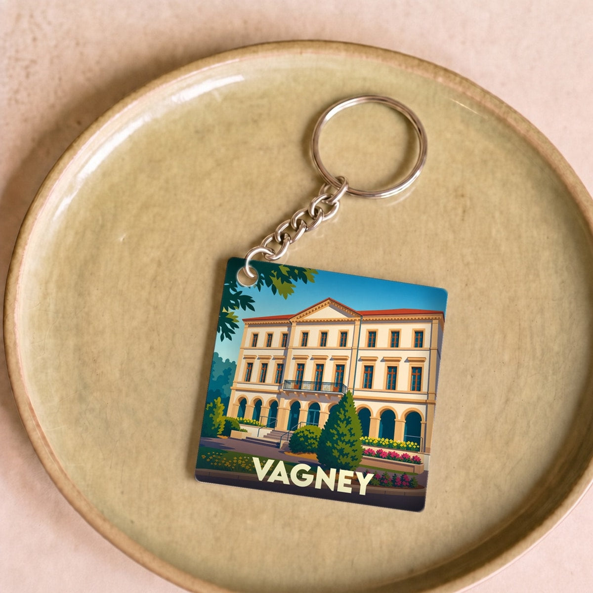 Porte-clés souvenir de la ville de Vagney avec une illustration stylisée d'un bâtiment remarquable.