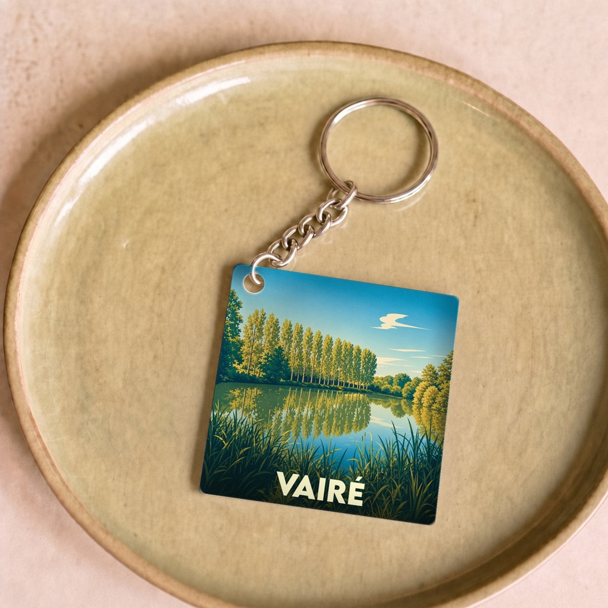 Porte-clés souvenir de la ville de Vairé avec une illustration stylisée d'un paysage naturel.