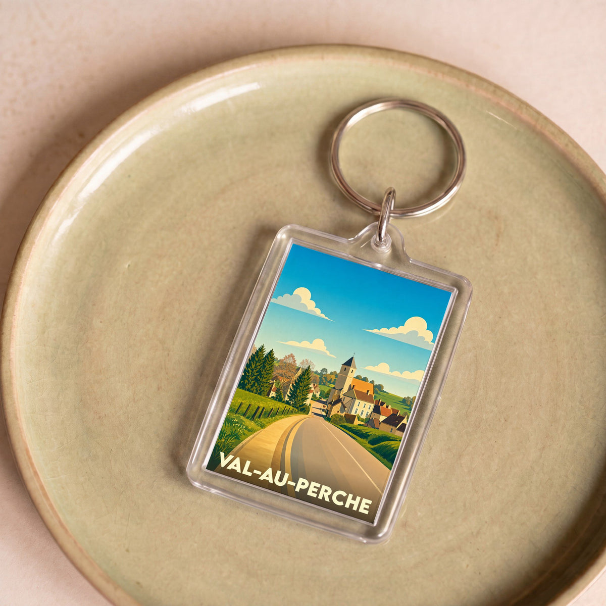 Porte-clés souvenir de la ville de Val-au-Perche avec une illustration stylisée.