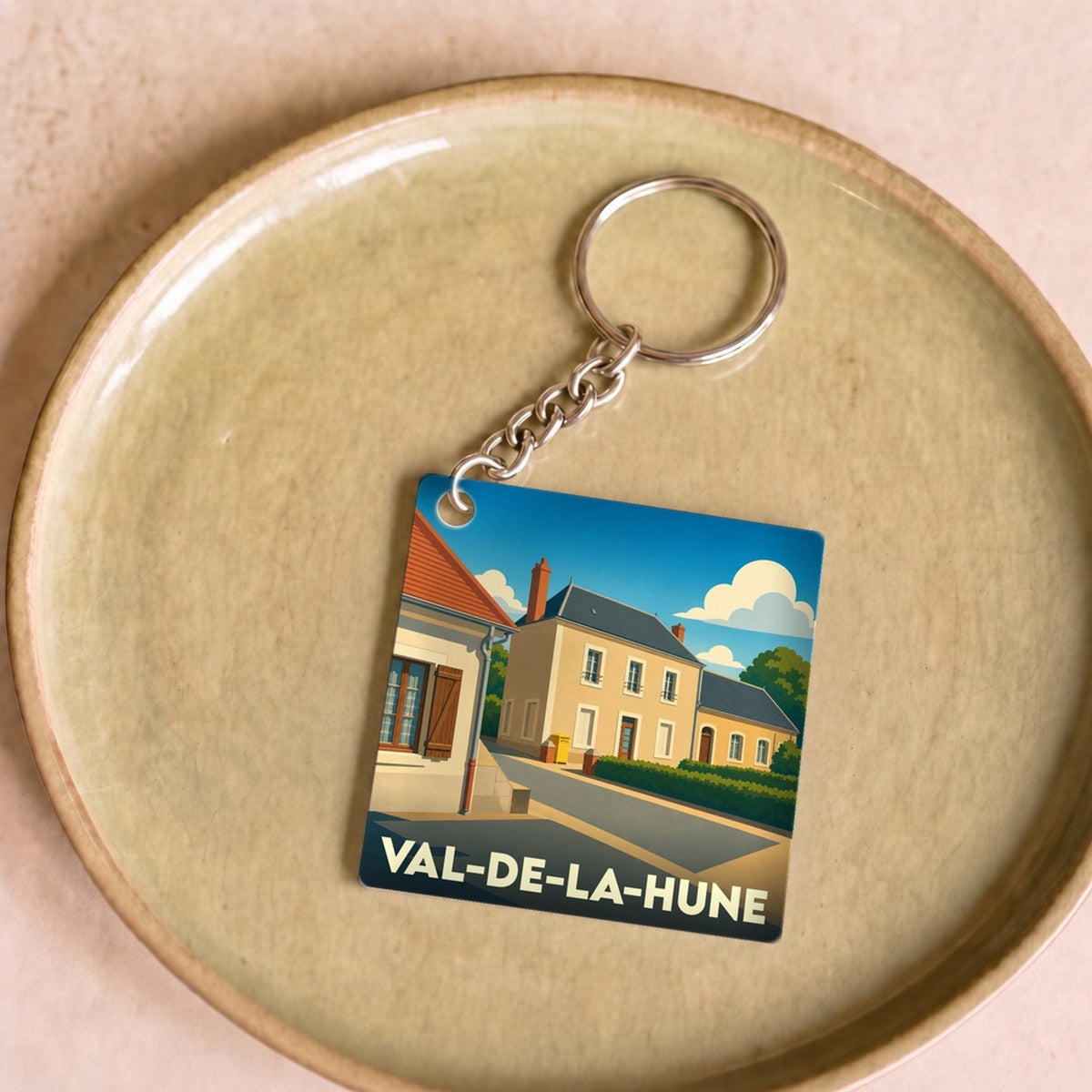 Porte-clés souvenir de Val-de-la-Hune avec une illustration stylisée d'un village français.