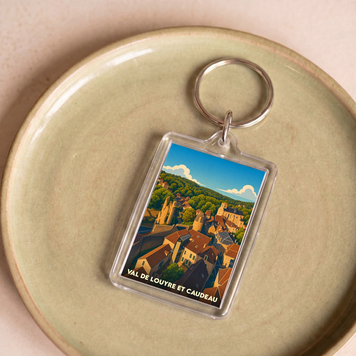 Porte-clés souvenir de Val de Louyre et Caudeau avec une illustration stylisée du village.