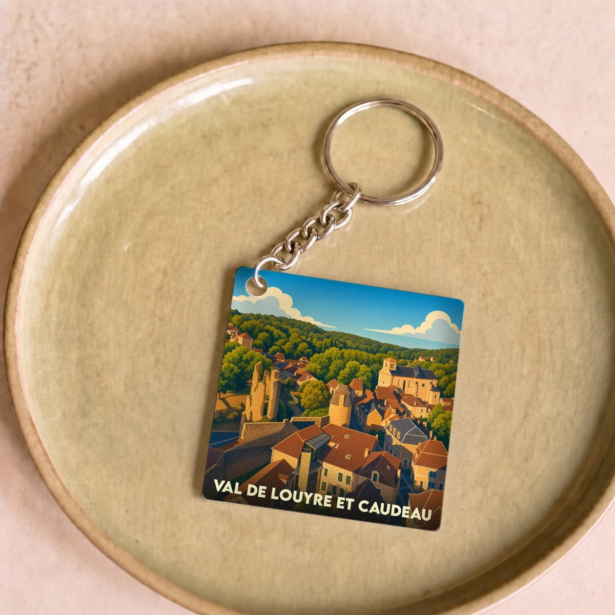 Porte-clés souvenir de Val de Louyre et Caudeau avec une illustration stylisée du village.