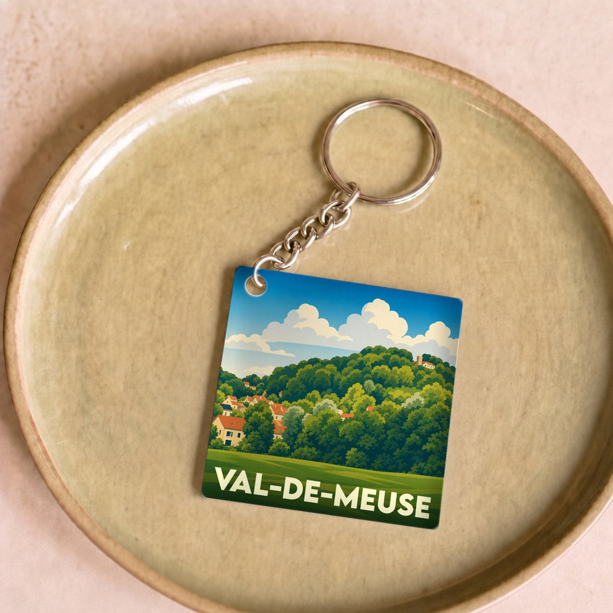 Porte-clés souvenir de Val-de-Meuse avec une illustration stylisée de paysages verdoyants.