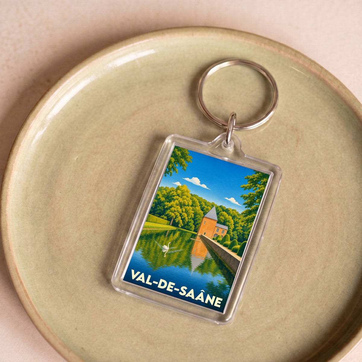 Porte-clés souvenir de la ville de Val-de-Saâne avec une illustration stylisée d'un château au bord de l'eau.