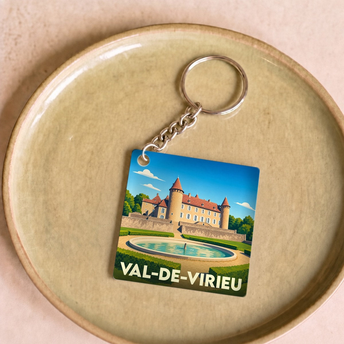 Porte-clés souvenir de la ville de Val-de-Virieu avec une illustration stylisée de son château et de ses jardins.