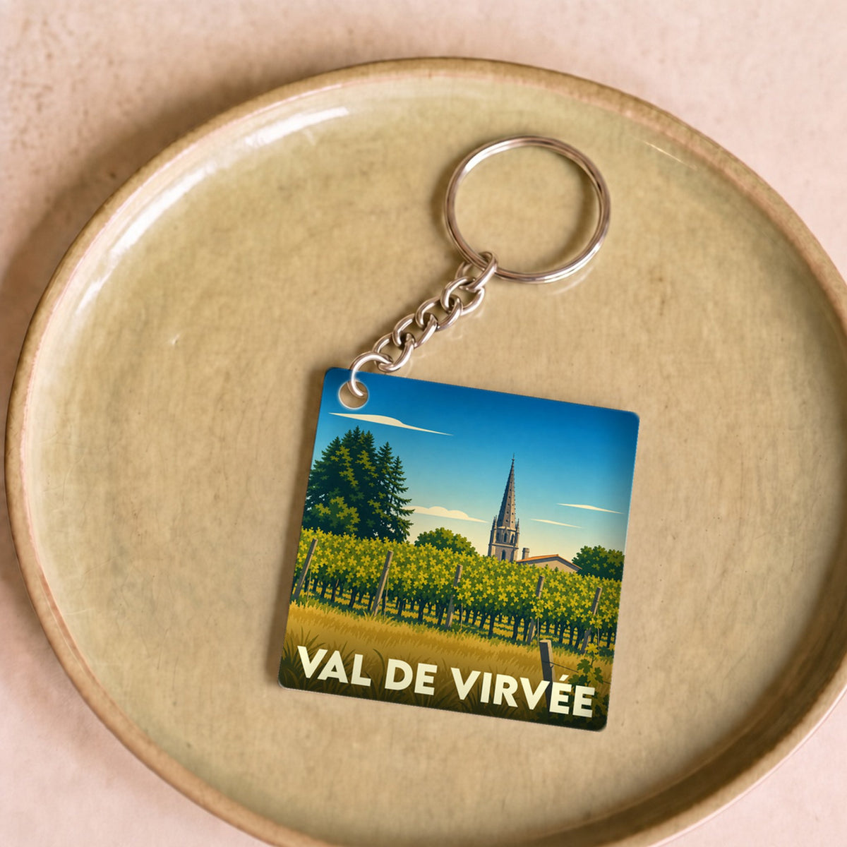 Porte-clés souvenir de Val de Virvée avec une illustration stylisée de vignobles et d'un clocher.