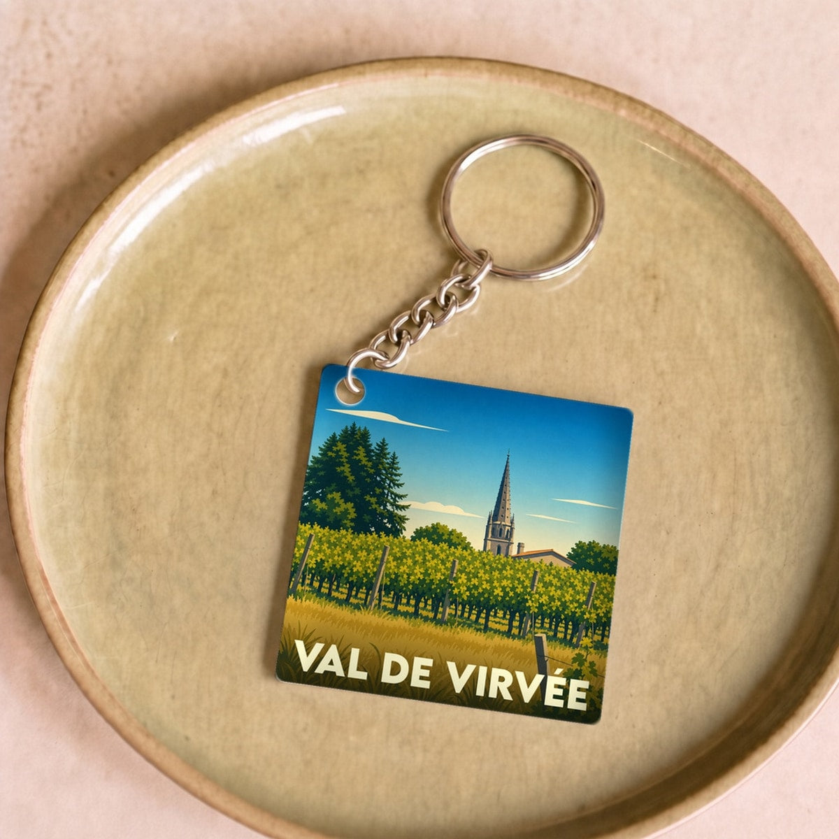 Porte-clés souvenir de Val de Virvée avec une illustration stylisée de vignobles et d'un clocher.