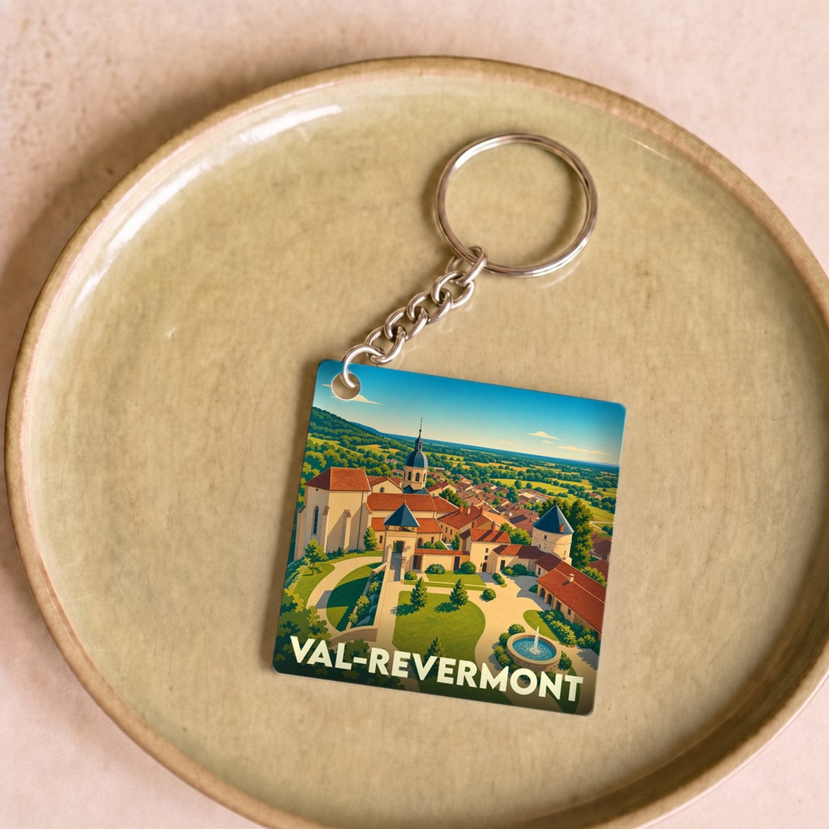 Porte-clés souvenir de la ville de Val-Revermont avec une illustration stylisée de son paysage urbain.