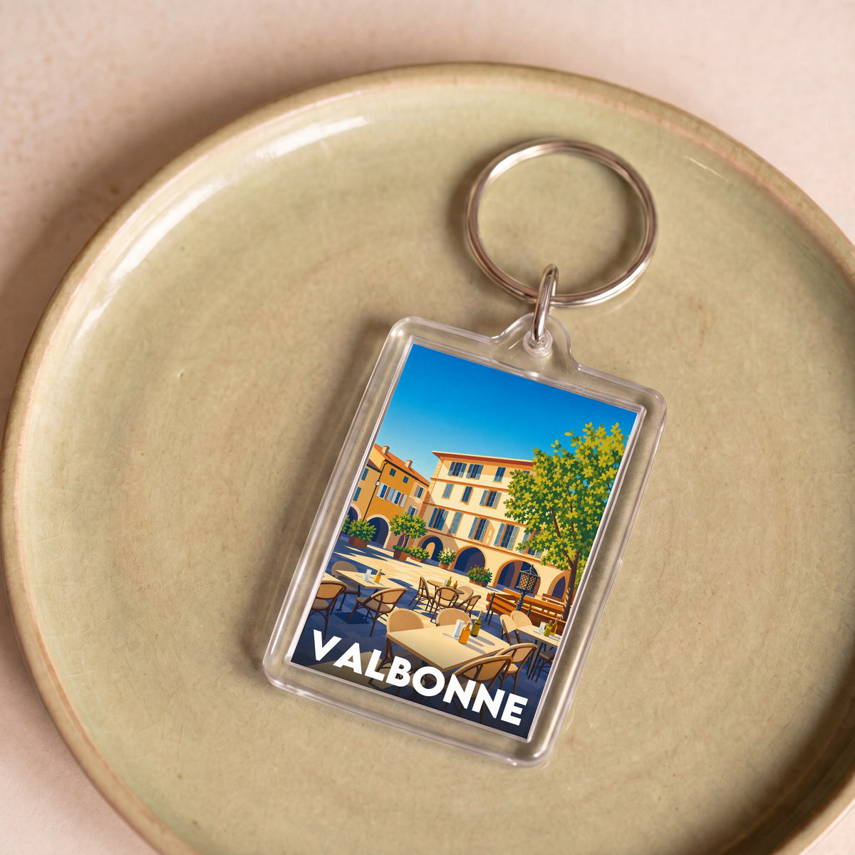 Porte-clés souvenir de la ville de Valbonne avec une illustration stylisée d'une place ensoleillée.