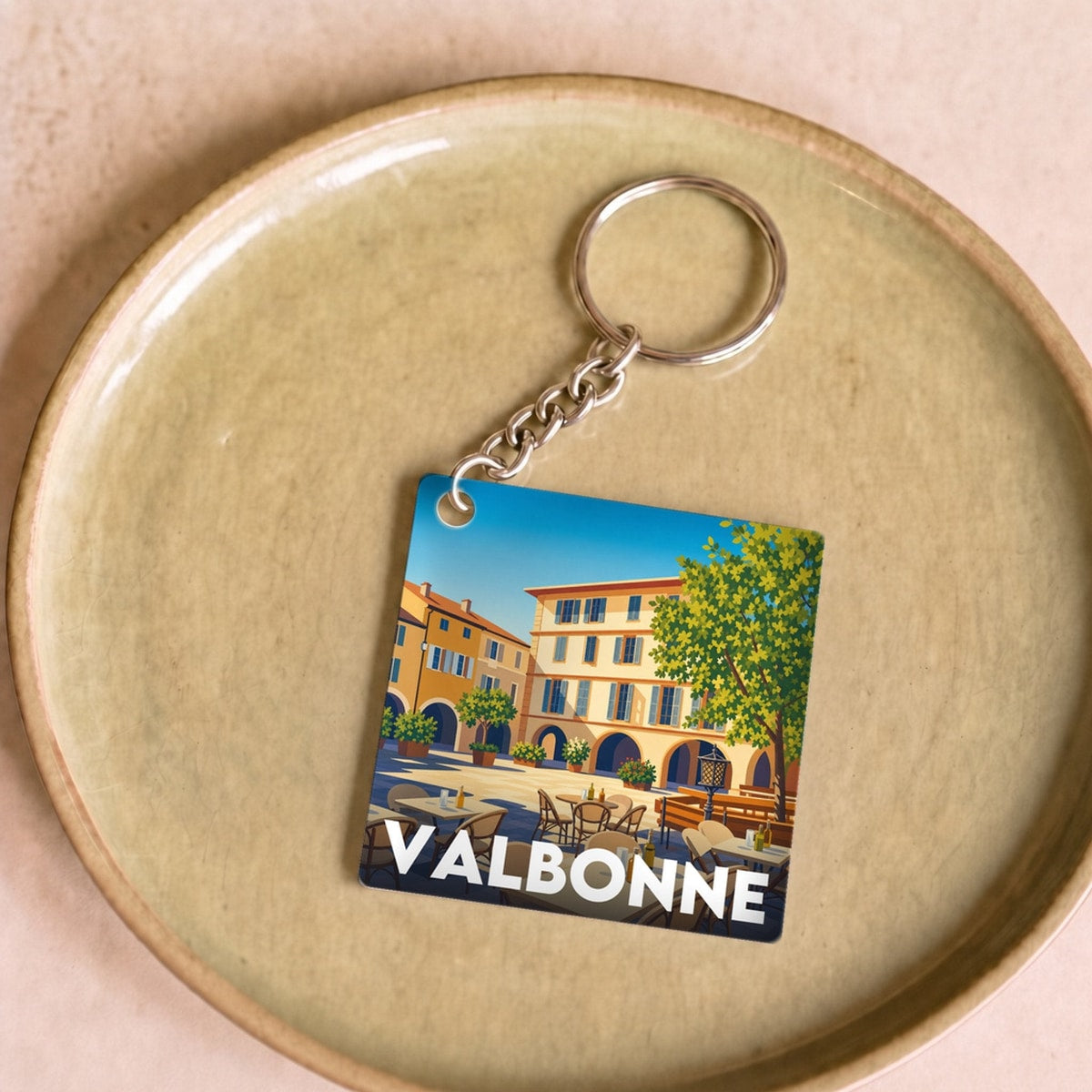 Porte-clés souvenir de la ville de Valbonne avec une illustration stylisée d'une place ensoleillée.