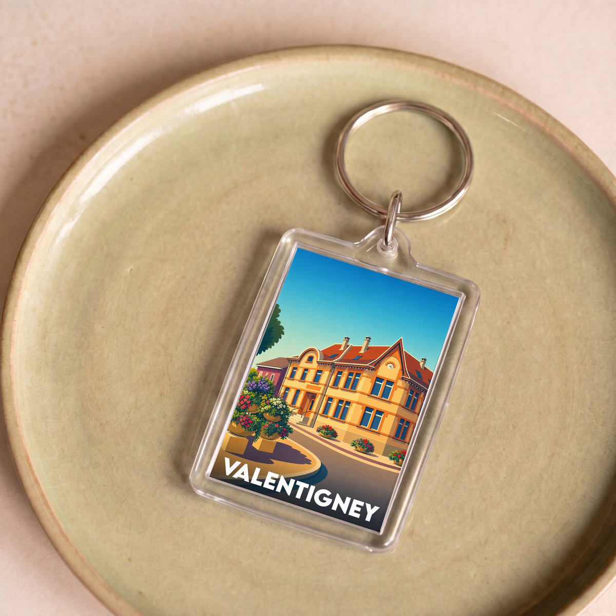 Porte-clés souvenir de la ville de Valentigney avec une illustration colorée et stylisée d'un bâtiment historique.