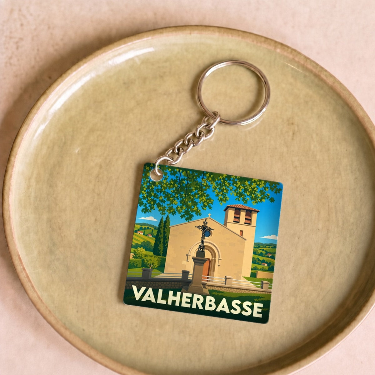 Porte-clés souvenir de la ville de Valherbasse avec une illustration stylisée d'une église locale.