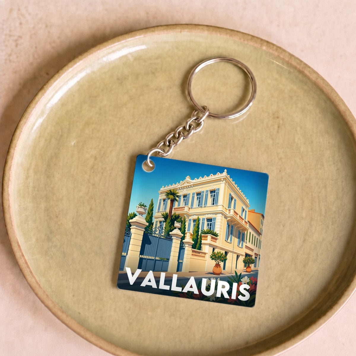 Porte-clés souvenir de la ville de Vallauris avec une illustration stylisée d'une villa.