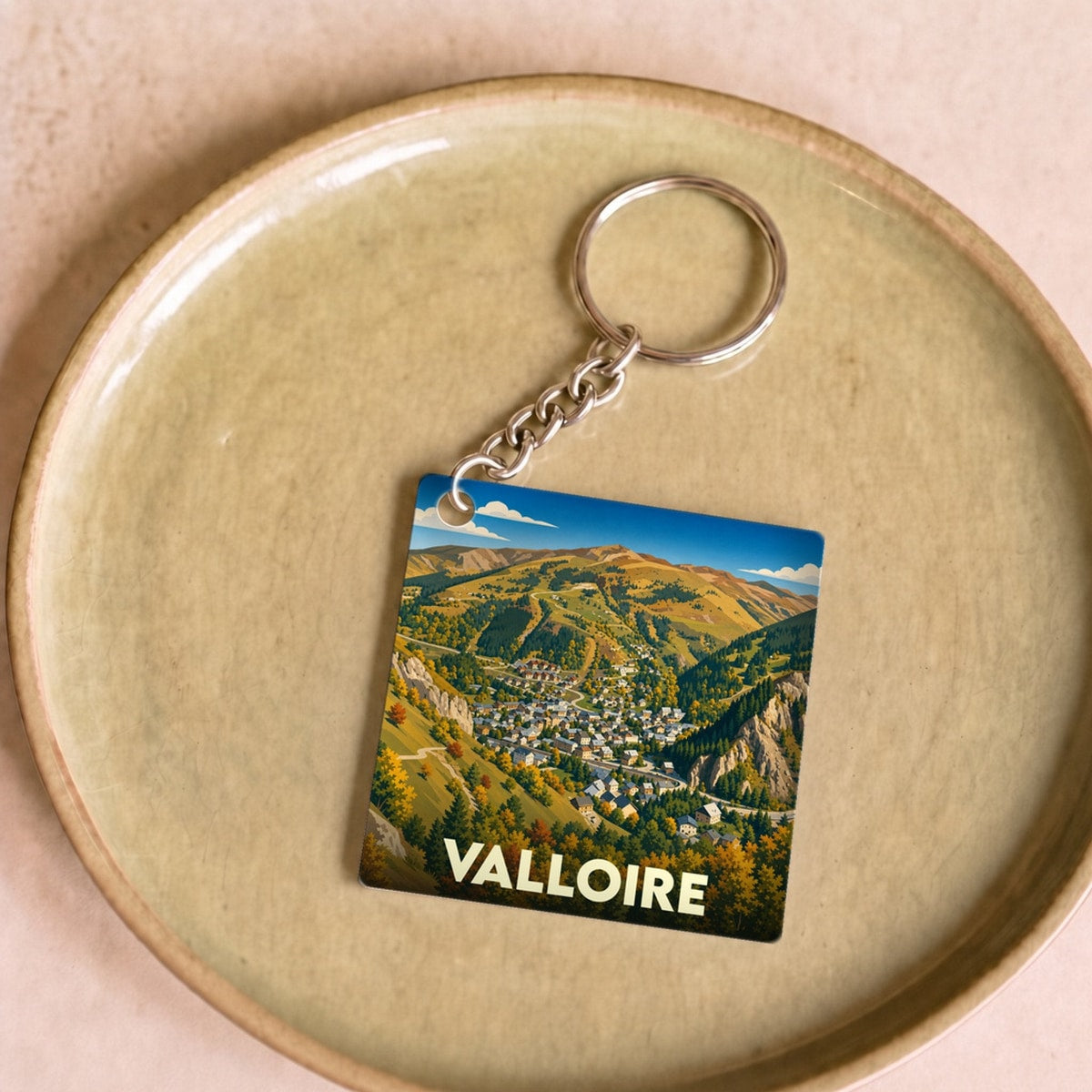 Porte-clés souvenir de la ville de Valloire avec une illustration stylisée de montagne en automne.
