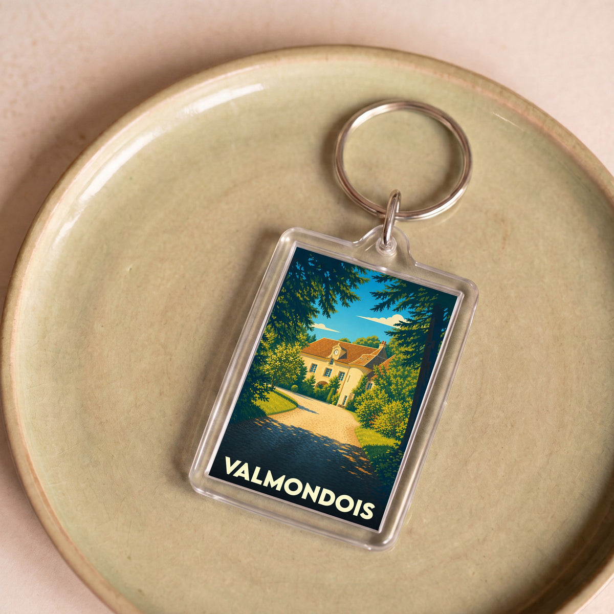 Porte-clés souvenir de la ville de Valmondois avec une illustration stylisée d'un manoir entouré de verdure.