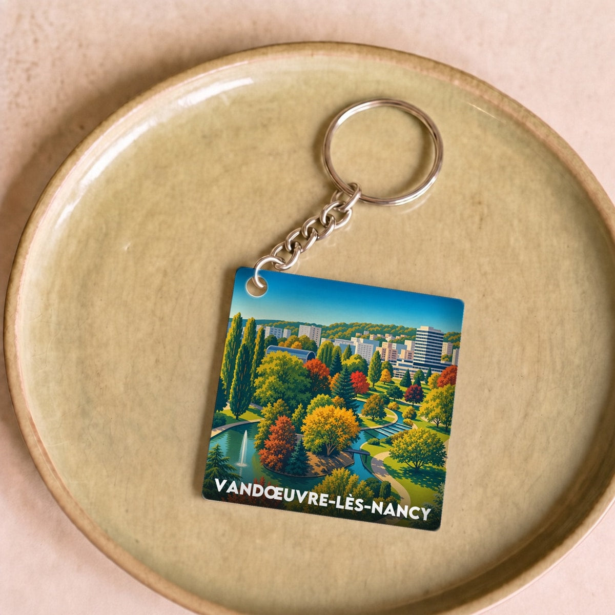 Porte-clés souvenir de la ville de Vandœuvre-lès-Nancy avec une illustration stylisée d'un parc arboré.