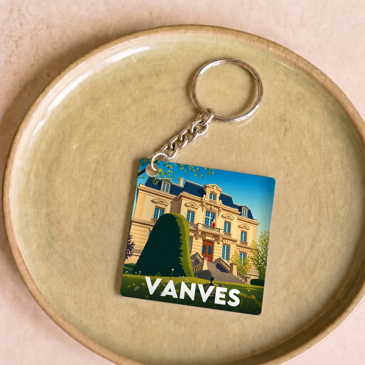 Porte-clés souvenir de la ville de Vanves avec une illustration stylisée d'un bâtiment historique.