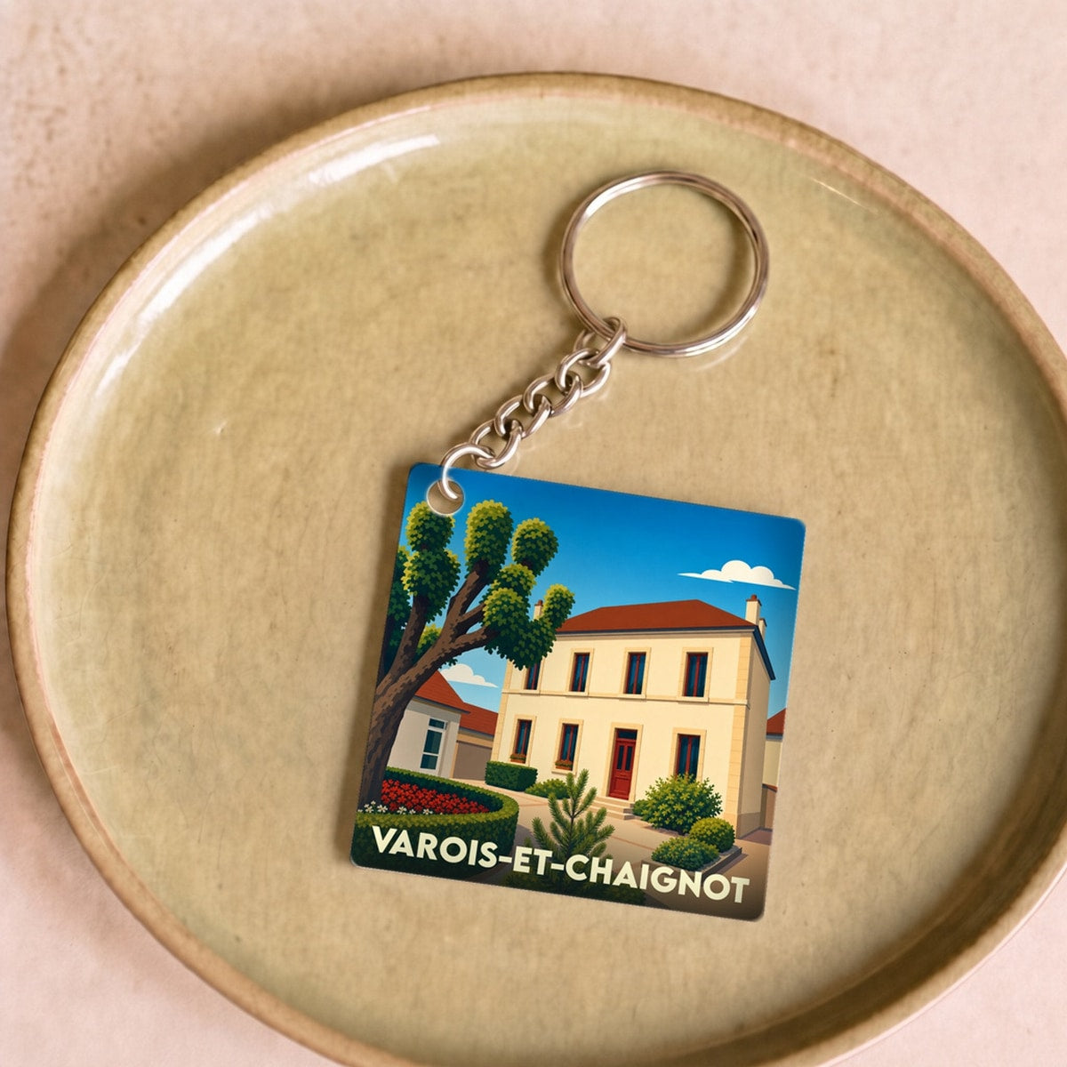 Porte-clés souvenir de la ville de Varois-et-Chaignot avec une illustration stylisée d'une maison de village.