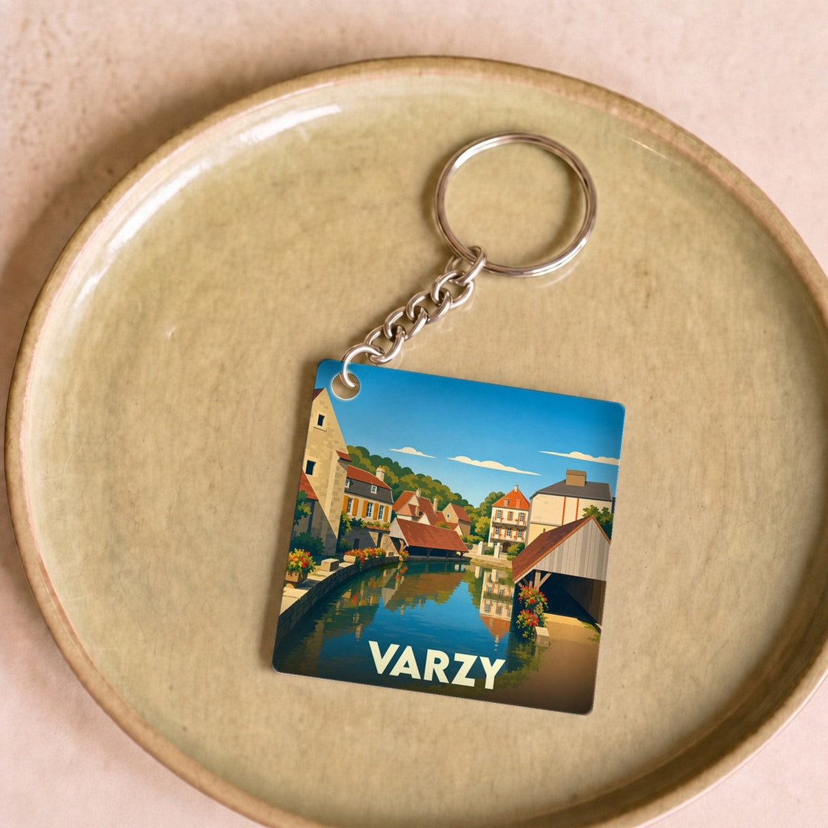 Porte-clés souvenir de la ville de Varzy avec une illustration stylisée d'un canal bordé de maisons.