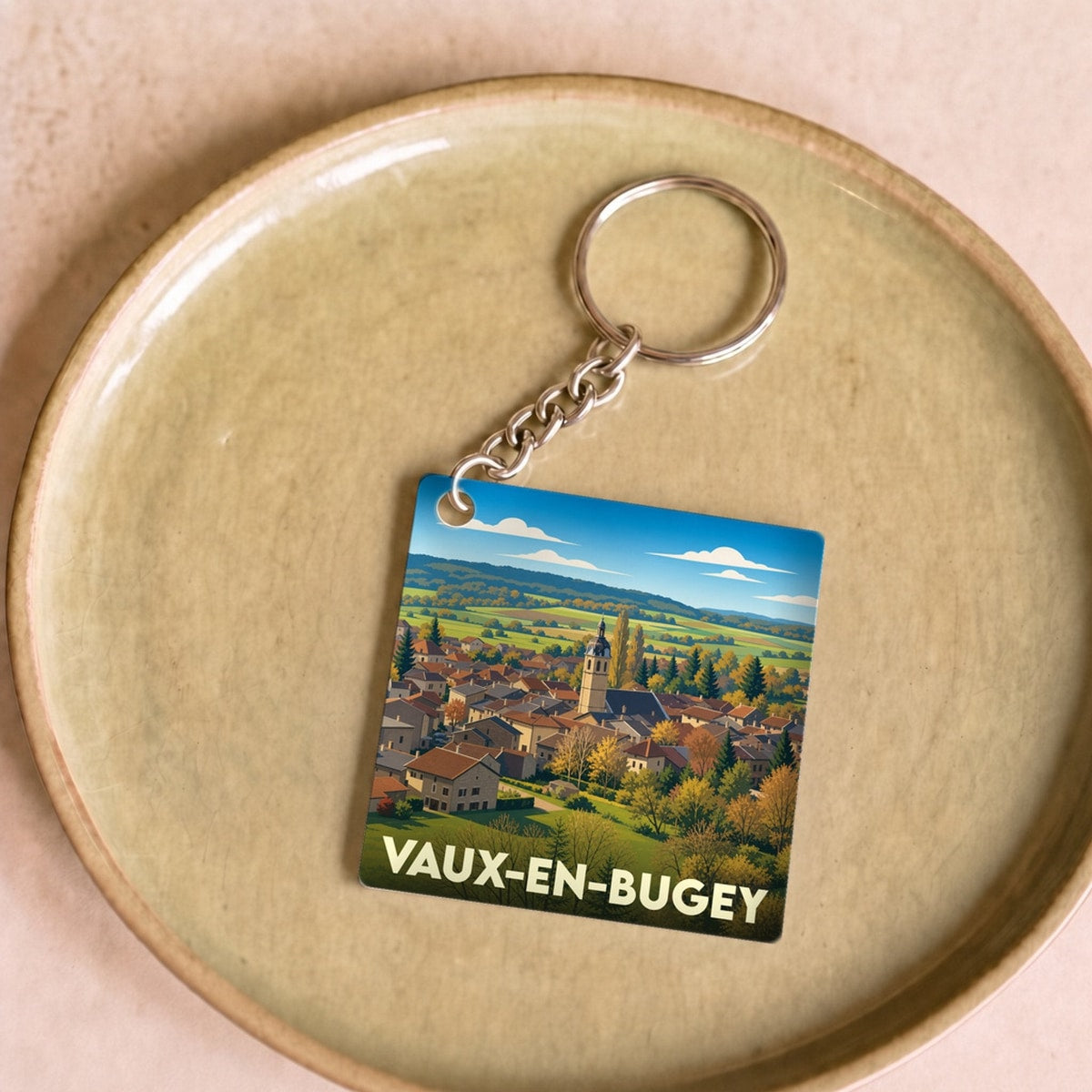 Porte-clés souvenir de la ville de Vaux-en-Bugey avec une illustration stylisée.