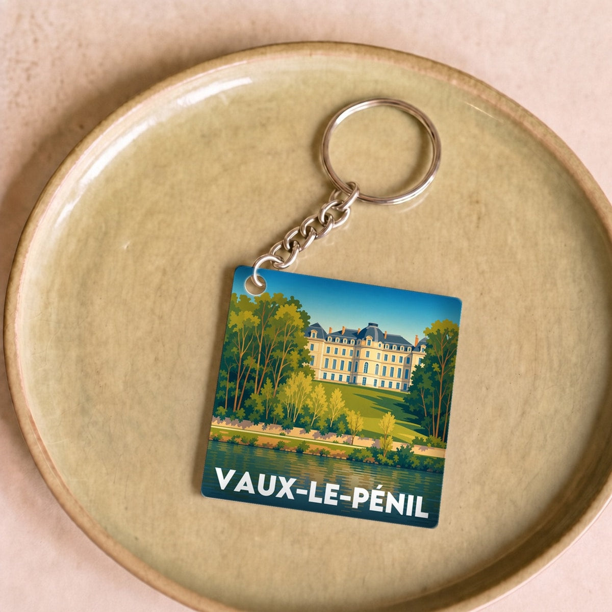 Porte-clés souvenir de la ville de Vaux-le-Pénil avec une illustration stylisée.