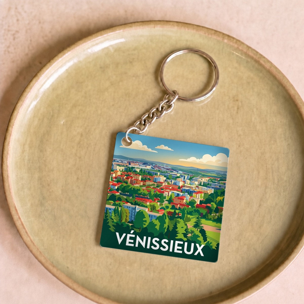 Porte-clés souvenir de la ville de Vénissieux avec une illustration stylisée du paysage urbain.